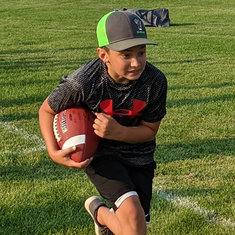 Youth Football Camp participant running with a football